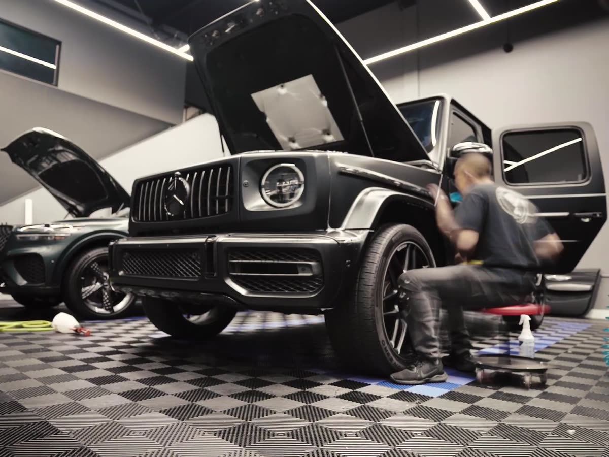 Oficina com um carro recebendo a película e um aplicador trabalhando